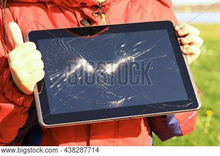 A Child Holds A Tablet In His Hands With A Broken Display