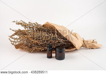 Dried Wormwood Herb, Artemisia Absinthiu, And Glass Bottles On White Background.