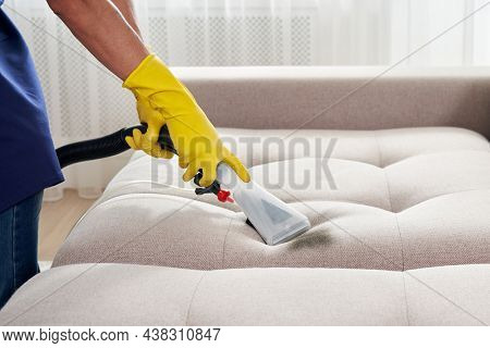 Close-up Of Housekeeper Holding Modern Washing Vacuum Cleaner And Cleaning Dirty Sofa With Stain Wit