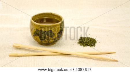 リネンの箸と緩い緑の茶のカップ