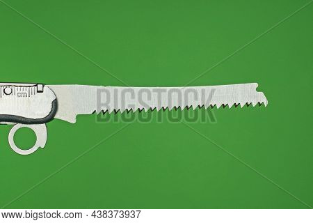 One Small Gray Metal Saw On The Handle Of A Multitool On A Green Background