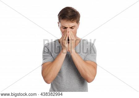 Sad Millennial Caucasian Guy Presses Hands To Nose And Suffers From Headache And Runny Nose
