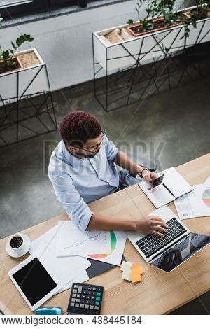 Overhead View Of African American Businessman Using Gadgets Near Documents In Office
