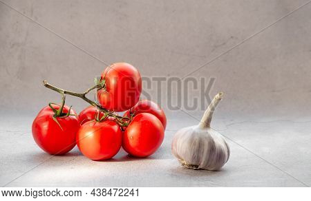 Fresh Tomatoes On A Vine With Garlic On A Light Background.
