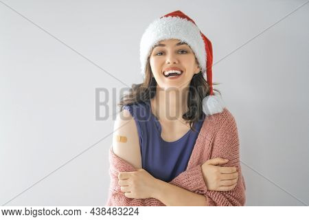 Young woman after vaccination wearing Santa hat. Virus protection on Christmas holidays. COVID-2019.