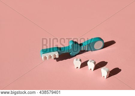 Three Teeth And A Blue Toothbrush Side By Side On A Pink Background. Proper Daily Brushing Of Teeth 