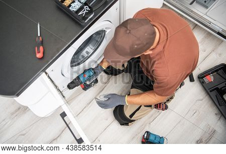 Professional Caucasian Cabinetmaker In His 40s Finishing Washer Cabinet Inside Clients Apartment.
