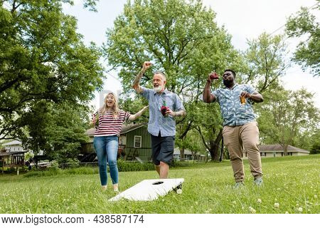 Friends playing cornhole at a summer party in the park
