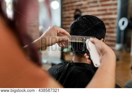Hairdresser trimming hair of the customer at a barbershop