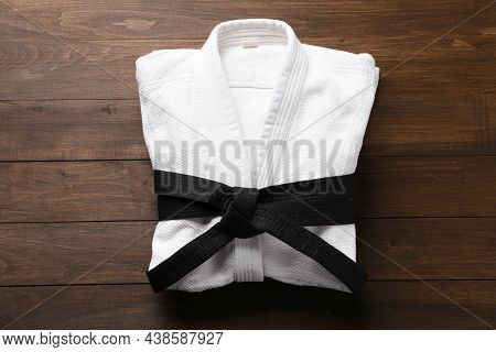 Martial Arts Uniform With Black Belt On Wooden Background, Top View