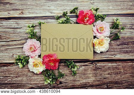 Frame Of Flowers With Paper Card For Text On Wooden Background