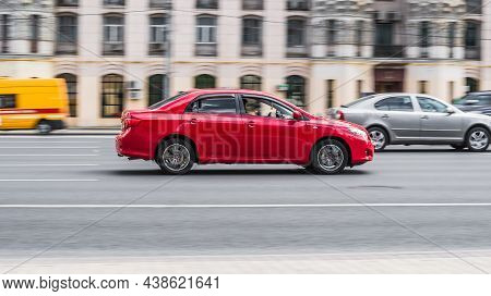 Side View Of Red Toyota Corolla E140. Fast Moving Car On The Street. Vehicle Driving Along The Stree