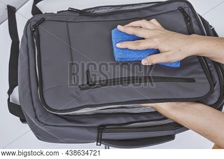 Cleaning Backpack With Washcloth. A Person Wipes Off Dirt Or Dust From The Outside Of The Bag. Wipin