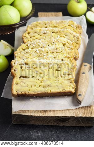 Sliced Apple And Coconut Oaf Cake On Wooden Cutting Board On Dark Background