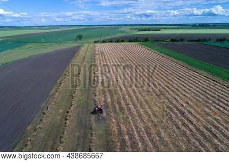 Top View Of Tractor With Hay Tedders Collecting Dry Lucerne For Balling In Field, Shoot From Drone