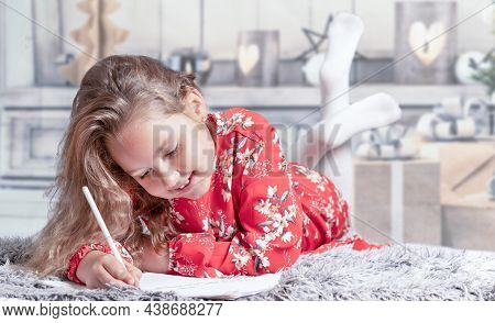 Girl Lying At Home In Red Dress Writing Letter For Christmas