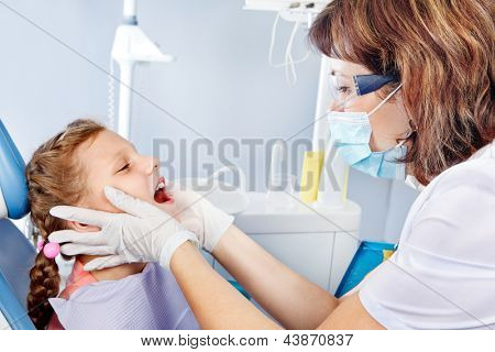 Ritratto di un dentista pediatrico esaminando i denti del bambino