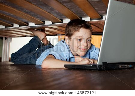 Enfant jeu portable sous le lit. Ordinateur Addiction