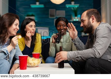 Multi-ethnic Friends Enjoying Spending Time Together Socializing During Wekeend Party Sitting On Cou
