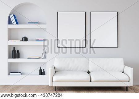 Two Empty Canvases On Wall Over Two Seater Sofa Near Arched Niche Shelf In White Living Room With Wo