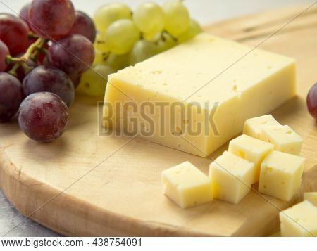 Light Meal With Sliced Cheese Next To A Bunch Of White And Red Grapes