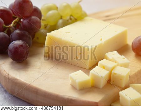 Light Meal With Sliced Cheese Next To A Bunch Of White And Red Grapes