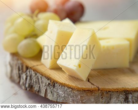 Light Meal With Sliced Cheese Next To A Bunch Of White And Red Grapes