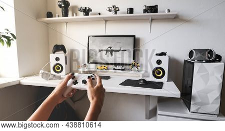 Close-up Of Female Hands Holding White Wireless Gamepad Against White Computer Dream Desk.