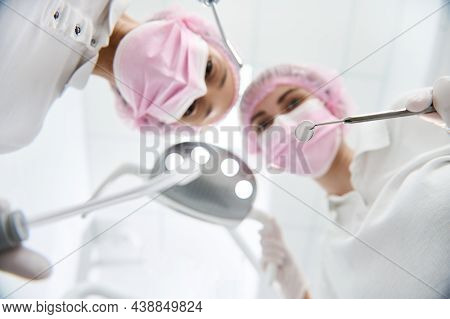 Soft Focus On A Stainless Steel Dental Mirror In The Hand Of A Blurred Female Surgeon Dentist Adjust