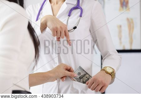 Close-up Of Female Hand Pointing To Pocket. Patient Bribing Cash To Practitioner. Corruption And Bri