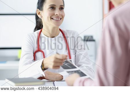 Portrait Of Smiling Gynecologist Looking At Patient With Gladness. Physician Pointing On Results Of 