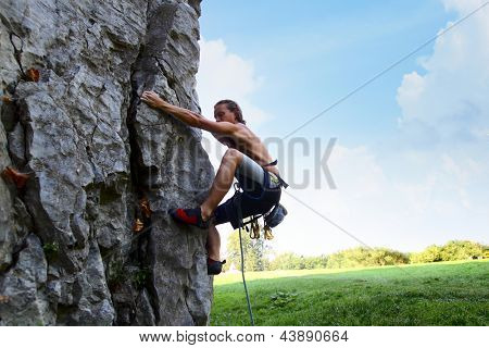 Joven escalada pared rocosa natural con cielo azul en el fondo
