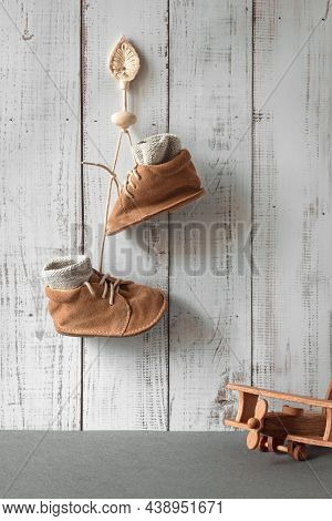 Newborn Things Background. Small Shoes Hang On A Hook In Children's Rooms, Vintage Toy Plane, Son Bi