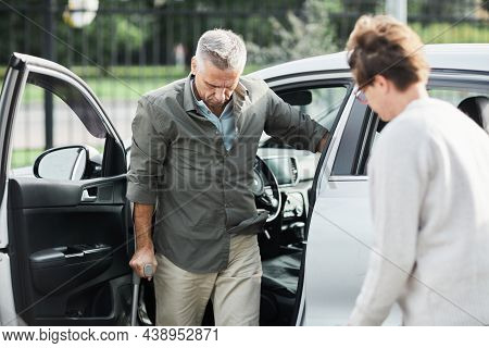Portrait Of Man With Disability Leaving Car Supported By Walking Cane, Copy Space