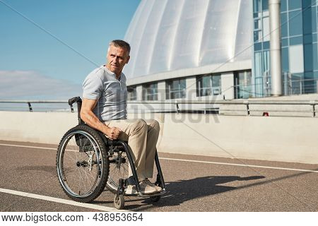 Side View Portrait Of Adult Man In Wheelchair On Bridge In Sunlight Enjoying City Life, Copy Space