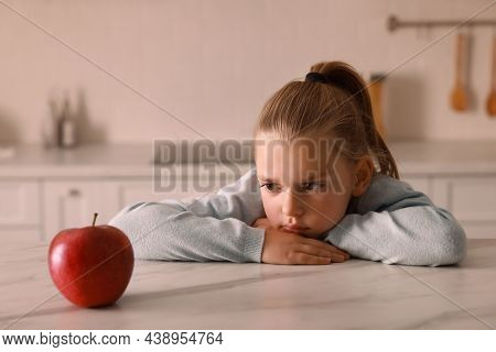 Cute Little Girl Refusing To Eat Apple In Kitchen
