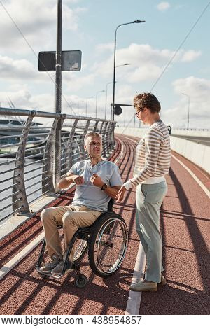 Vertical Portrait Of Adult Couple With Man In Wheelchair In Accessible City Environment Outdoors Lit
