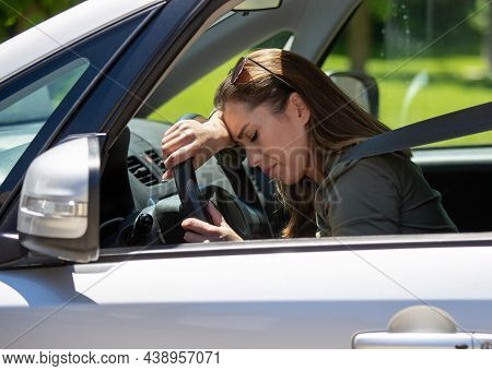 Exhausted Girl Resting In Car After Driving. Tired Woman Leaning On Streering Wheel With Eyes Closed