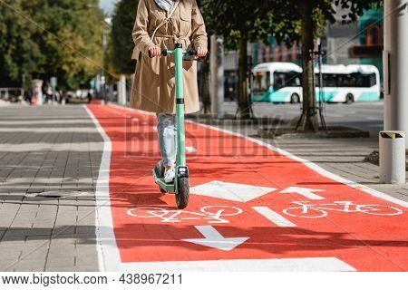 traffic, city transport and people concept - woman riding electric scooter along red bike lane with signs of bicycles and two way arrows on street