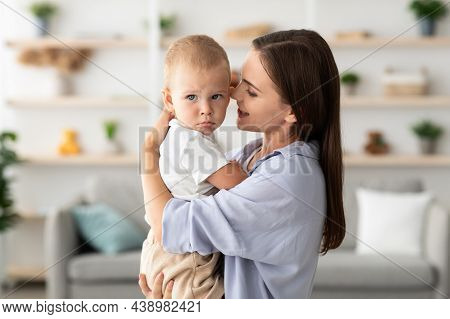 Mothers Care Concept. Beautiful Young Woman Holding Adorable Toddler Child In Hands,