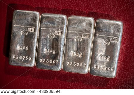 Four Cast Silver Bars Weighing 250 Grams Each On A Burgundy Textured Background. Silber Is Silver.