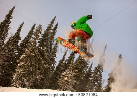 Snowboarder jumping through air with deep blue sky in background