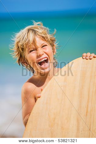 Happy Young boy having fun at the beach on vacation, with skimboard