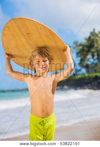 Happy Young boy having fun at the beach on vacation, with skimboard