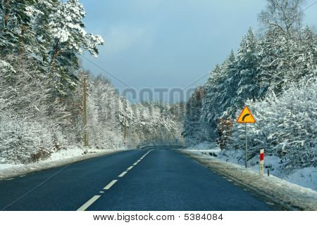 Verschneite Straße mitten im Wald