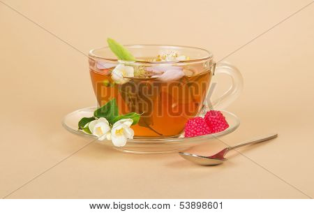 Cup of flower tea spoon and raspberry on beige