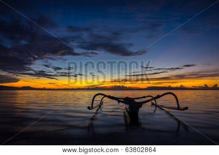 Fisherman out-rigger boat on the shallow water on Bali beach at sunrise