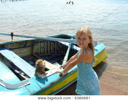 La petite fille en robe bleue se trouve près du bateau