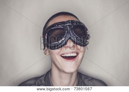 happy girl in retro pilot glasses over grey background