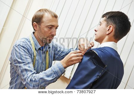 male tailor designer make marks on a jacket during bespoke suit fitting